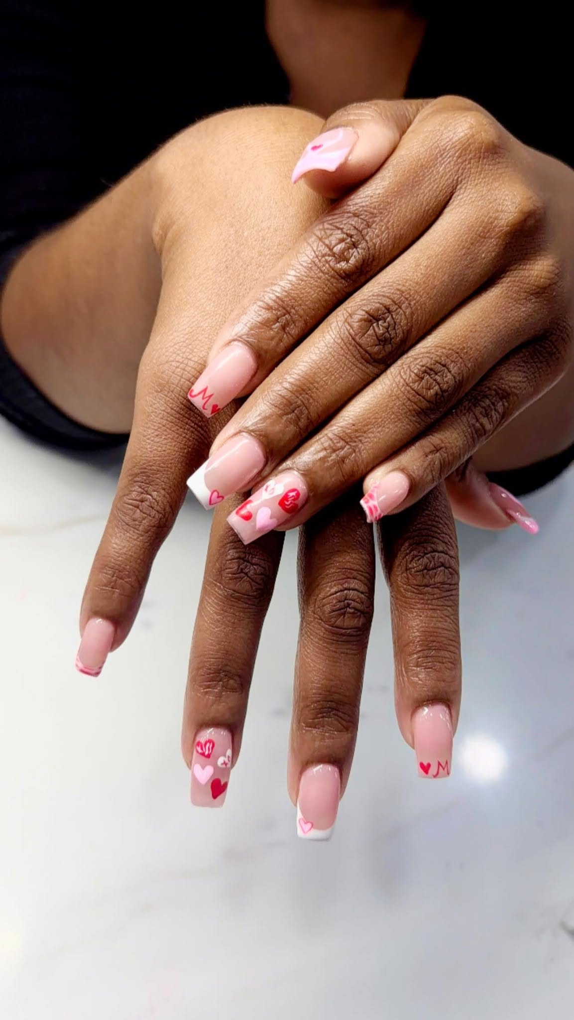 Pink Valentine nail art with hearts and French tips